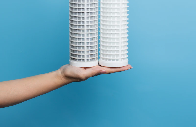 Hand holding a new RO filter cartridge before replacement